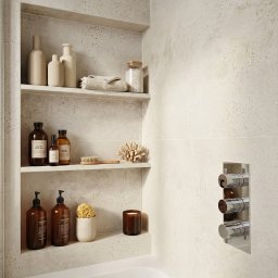 Harmony Ewa Jaworska - Narożna półka w łazience wyłożona beżowymi kaflami Moonrow white, z kosmetykami i świecą, nad białą wanną. Chromowana bateria termostatyczna.