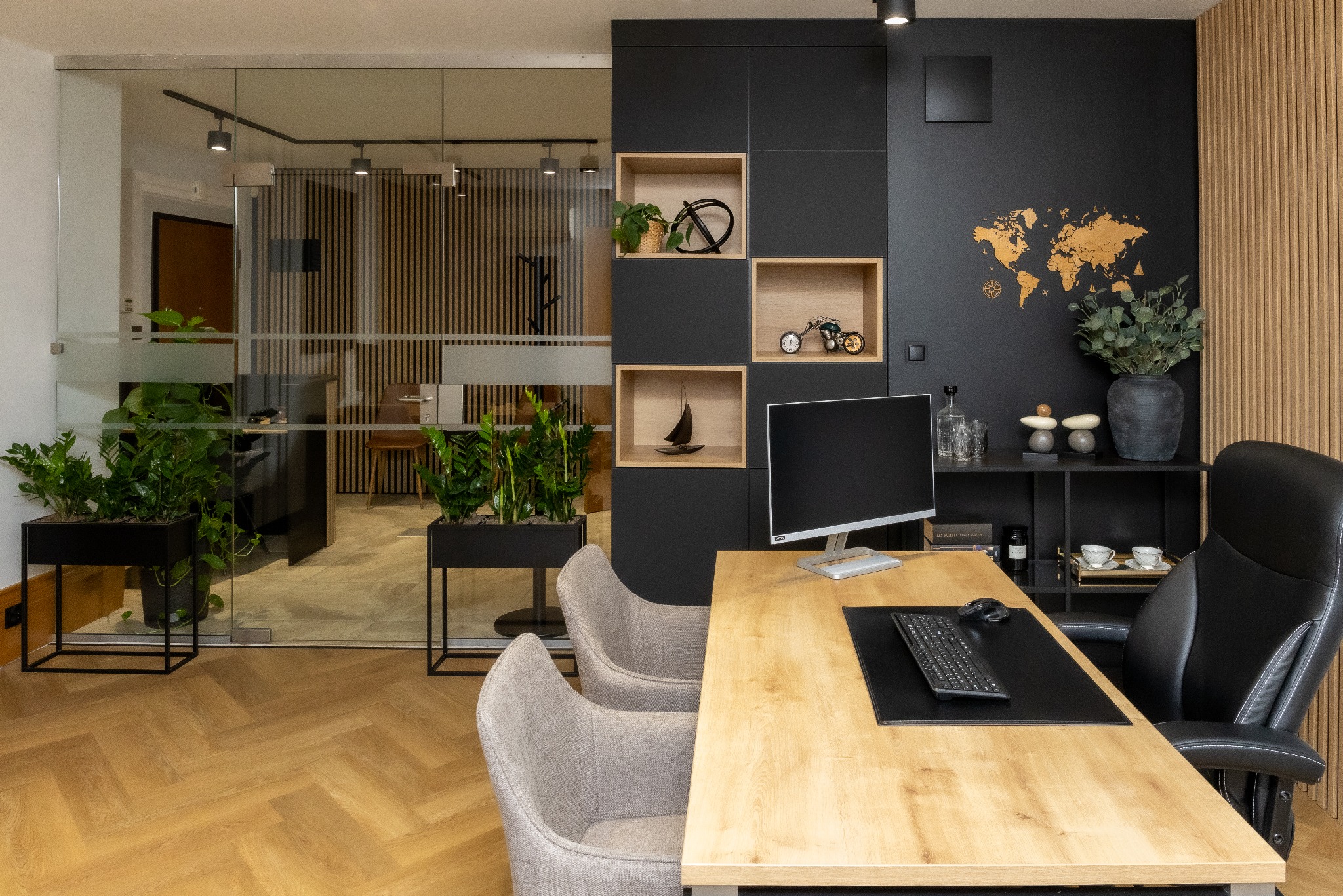 Nowoczesne biuro z drewnianym biurkiem, ergonomicznym krzesłem i dekoracjami: mapa świata, rośliny, minimalistyczne półki. Przeszklone ściany oddzielają przestrzeń.