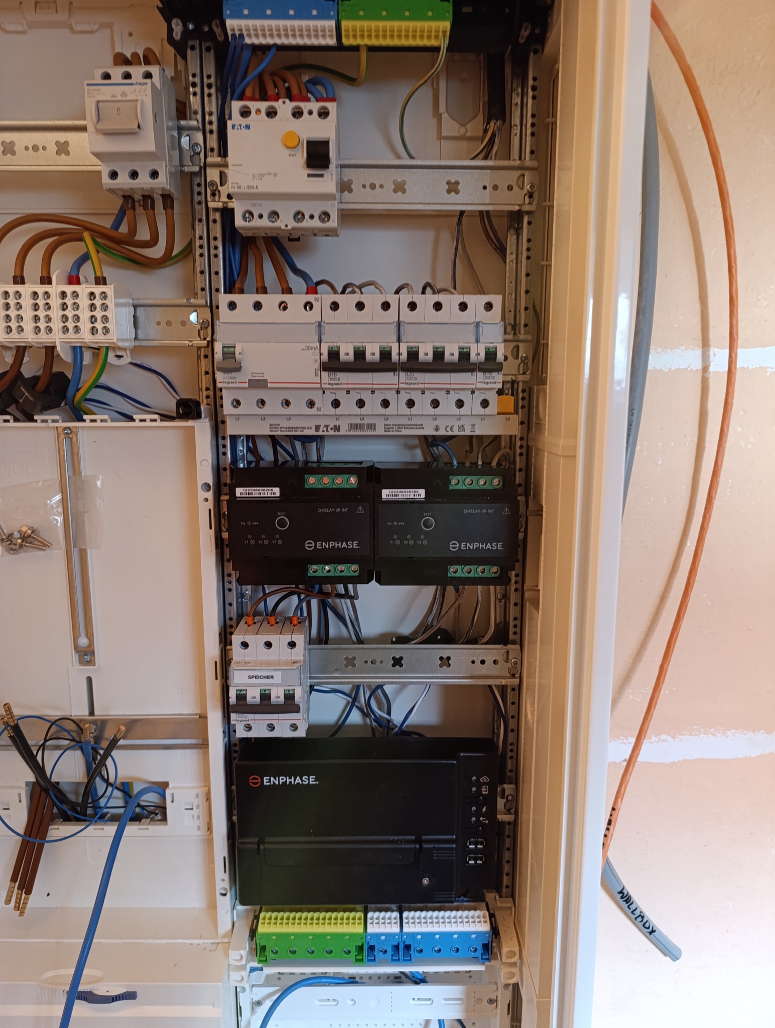 Rozdzielnica elektryczna z zainstalowanymi modułami Enphase, bezpiecznikami Legrand i Eaton. Widoczne przewody i listwy zaciskowe. Całość w białej obudowie.