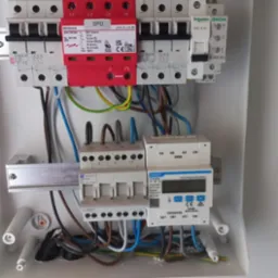 Wnętrze skrzynki elektrycznej z zamontowanym modułem SPD (ochrona przeciwprzepięciowa), bezpiecznikami i licznikiem energii. Widoczne okablowanie i listwy zaciskowe.