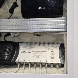 Szuba Volt System - Rozdzielacz sygnału SAT Signal MP-0908 z podłączonymi kablami koncentrycznymi, router TP-Link i kable sieciowe w białej wnęce. Widoczne złącza i oznaczenia.