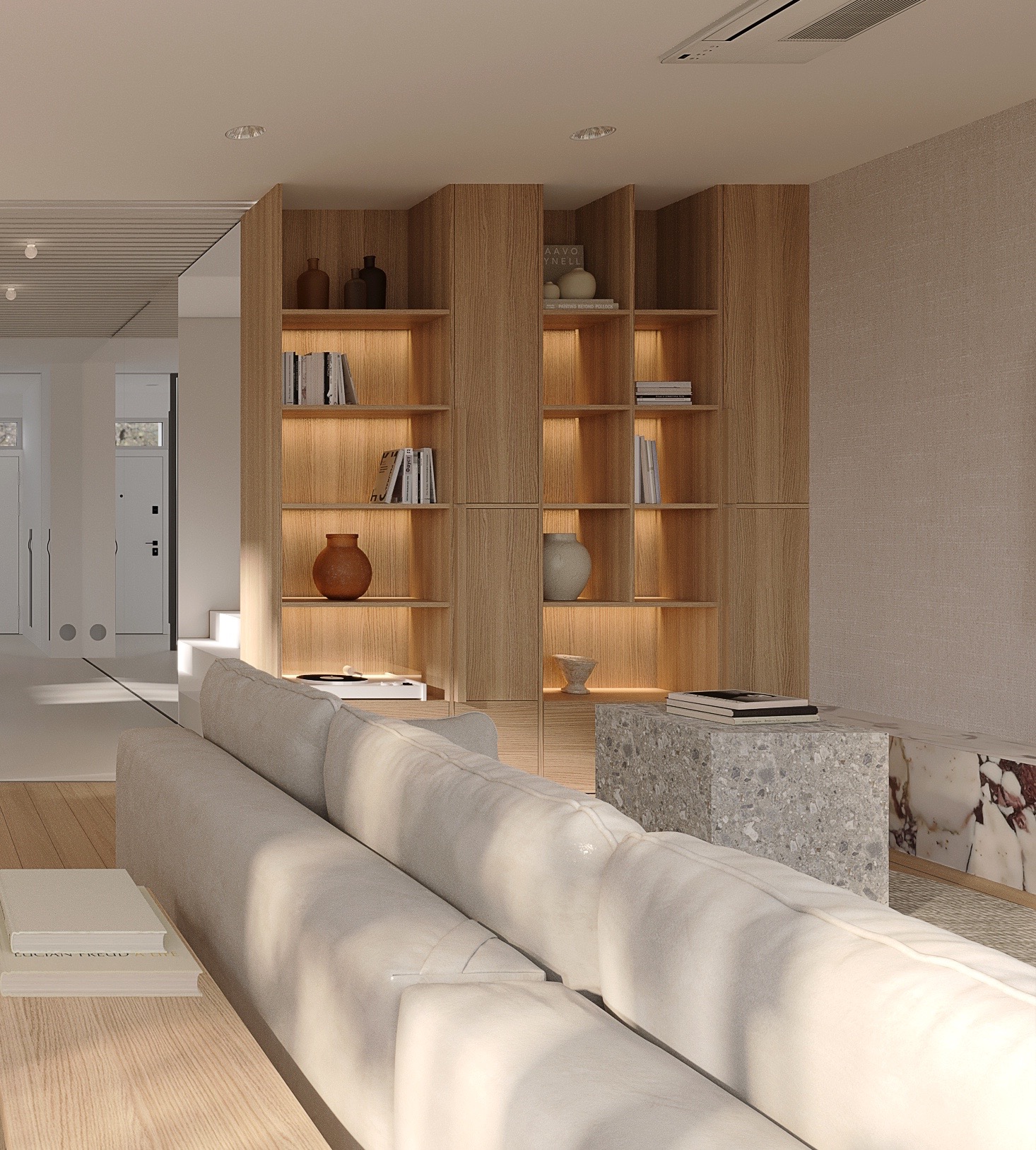 Jasne wnętrze salonu z drewnianym regałem podświetlonym od wewnątrz, szarą sofą i stolikiem z lastryko. Widoczne książki, wazony i elementy dekoracyjne.