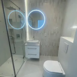 Nowoczesna łazienka w odcieniach szarości z podświetlanym lustrem, kabiną prysznicową i podwieszaną toaletą. Minimalistyczny design, płytki imitujące cegłę.