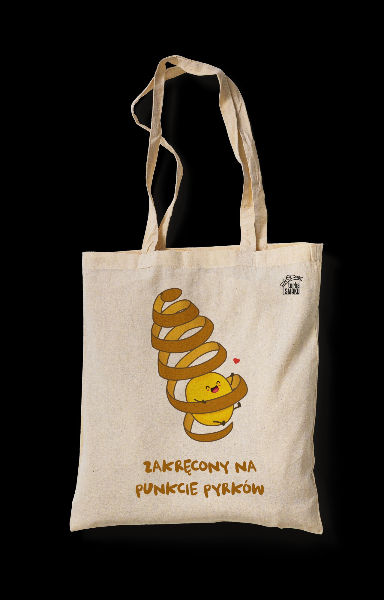 Beżowa torba bawełniana z nadrukiem uśmiechniętego ziemniaka otulonego spiralą obierki i napisem 'Zakręcony na punkcie pyrków', na czarnym tle.