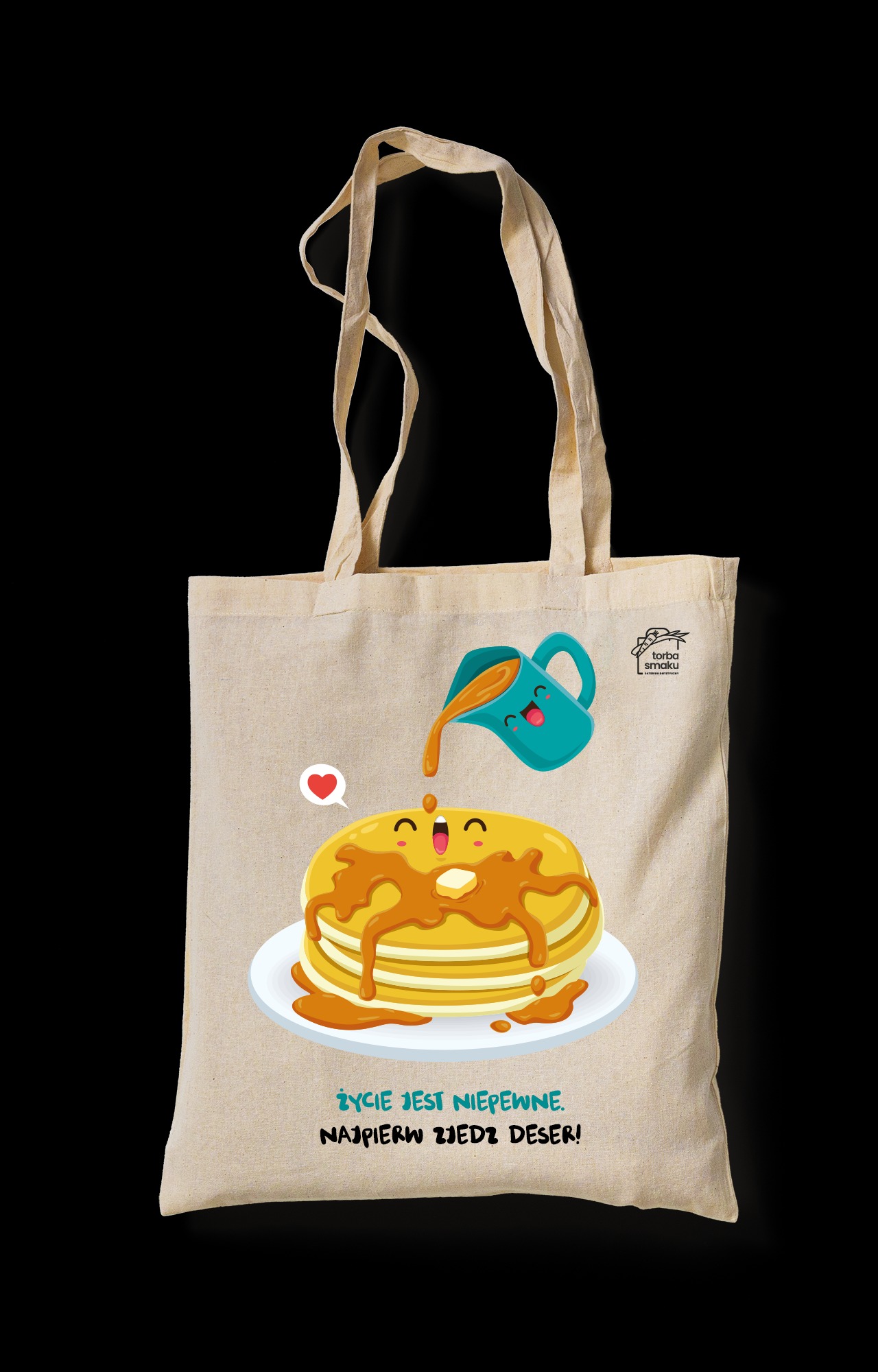 Beżowa torba bawełniana z nadrukiem graficznym: uśmiechnięte naleśniki polewane syropem z wesołego dzbanka, obok logo 'Torba Smaku' i napis 'Życie jest niepewne. Najpierw zjedz deser!'