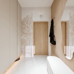 Kwiatkowska Studio - Jasny przedpokój z szafą w zabudowie, drewnianą ścianą z wieszakami i okrągłym lustrem, wzorem drzewa na ścianie oraz białą ławką.