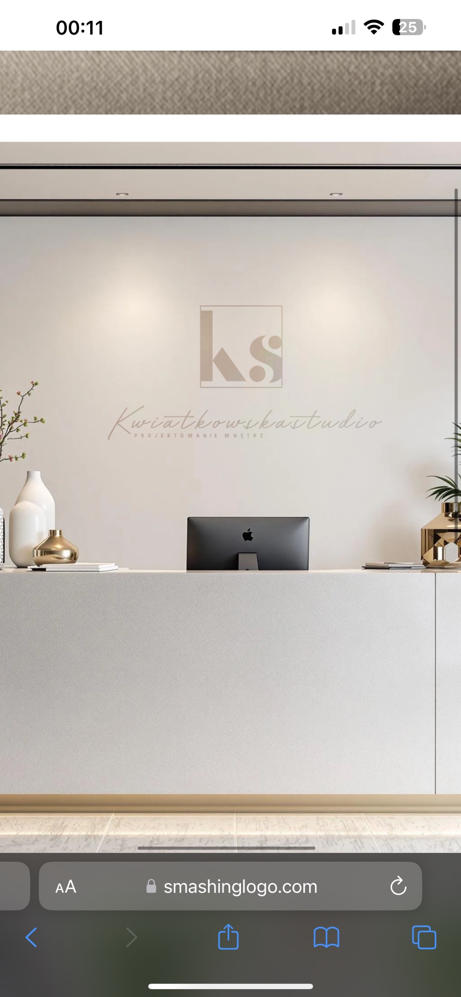 Recepcja biura z logo 'KS' i napisem 'Kwiatkowska Studio Projektowanie Wnętrz' na ścianie, minimalistyczny design, białe i złote akcenty dekoracyjne, monitor Apple w tle.