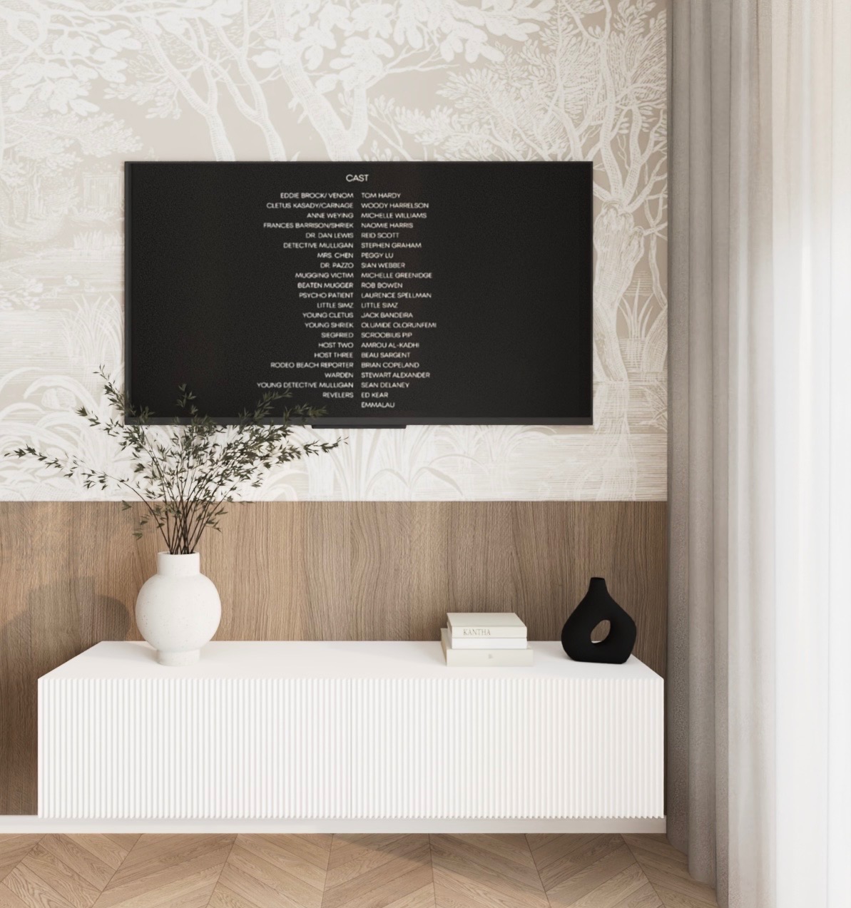 Telewizor z wyświetlonymi napisami końcowymi filmu, umieszczony na tle ściany z tapetą w motywy drzew i drewnianą boazerią. Poniżej biała szafka RTV z wazonem z gałązkami i czarnym, dekoracyjnym...