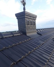 Czarny, ceramiczny dach z kominem wykończonym w tym samym stylu, widok z góry, na kominie ozdobna instalacja odgromowa.