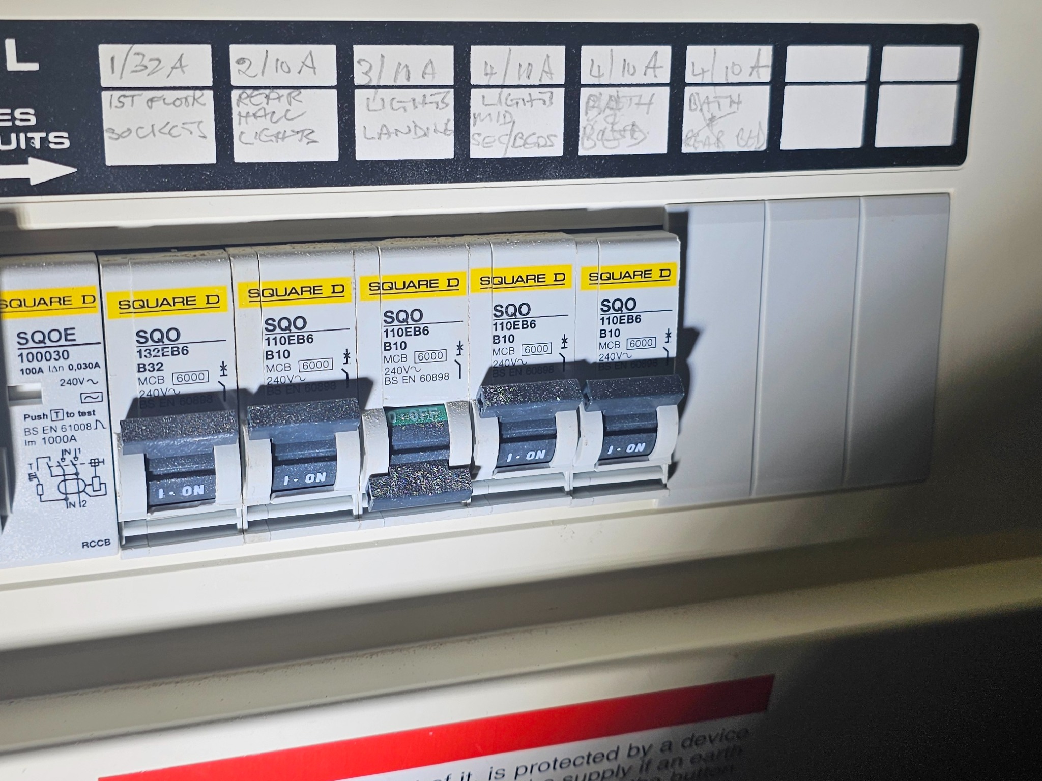 Rozdzielnica elektryczna Square D z opisami obwodów (1/32A, 2/10A, 3/NA, 4/10A) i wyłącznikami, gdzie jeden wyłącznik jest w pozycji OFF.