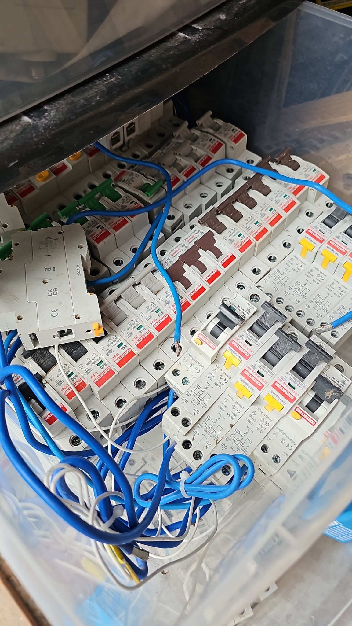 Skrzynka z bezpiecznikami i przewodami elektrycznymi. Różne typy bezpieczników ułożone obok siebie, widoczne niebieskie przewody.