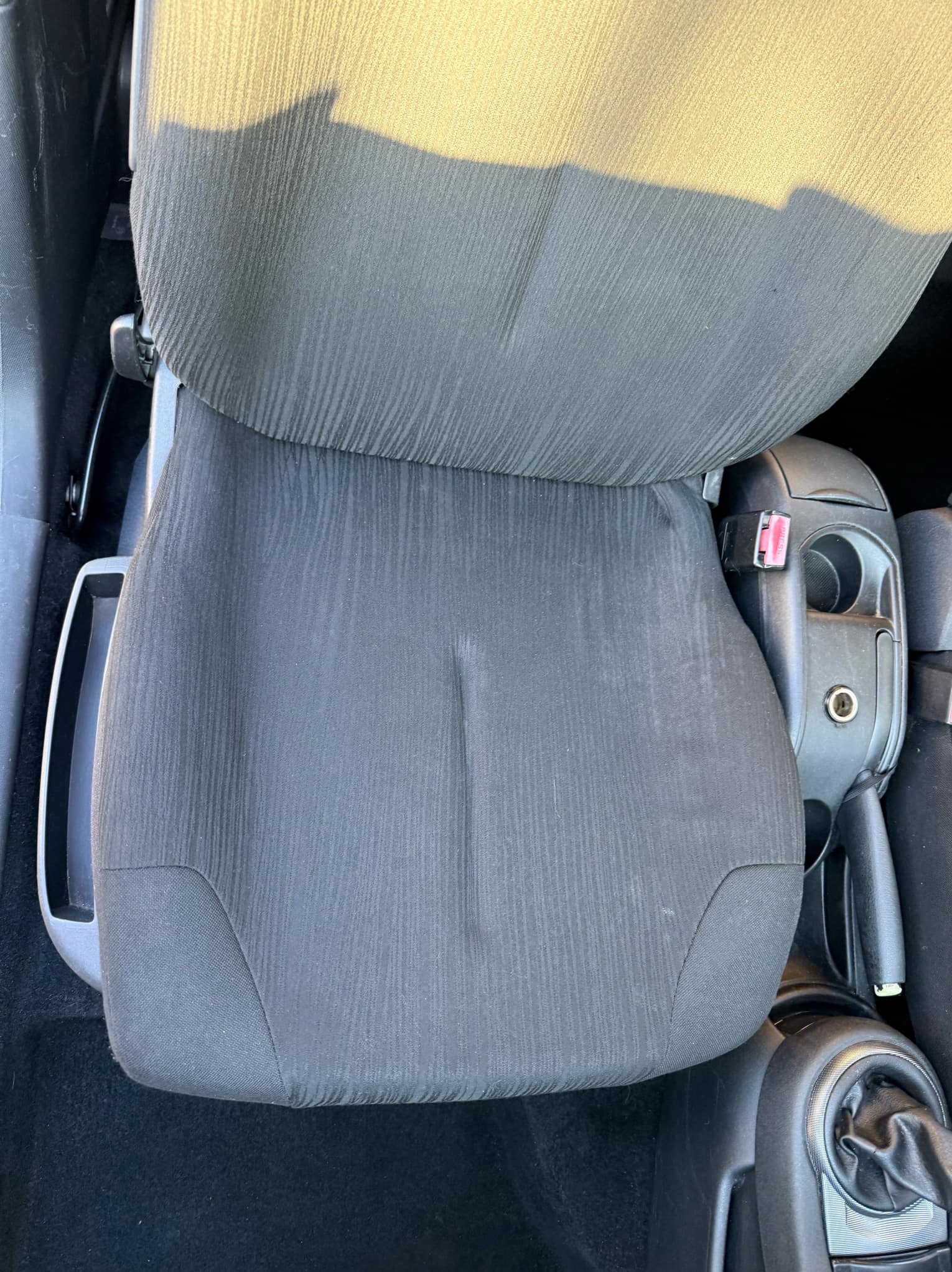 Czyszczenie tapicerki samochodowej w Sobótce: zbliżenie na czarny fotel samochodowy z widocznym zabrudzeniem przed czyszczeniem.