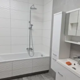 Nowoczesna łazienka w bieli i szarościach: wanna z mozaikową obudową, kabina prysznicowa, umywalka z szafką i lustrem. Minimalistyczny design, gładkie płytki.