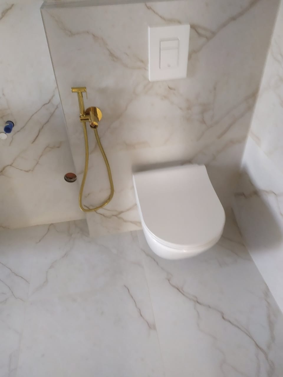 Nowoczesna toaleta z bidetką w kolorze złota, biała armatura na tle marmurowych płytek. Minimalistyczny design, czystość i elegancja w detalu.