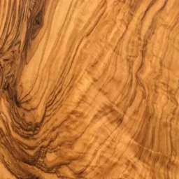 Zbliżenie na naturalny, wzorzysty fornir z drewna oliwnego. Unikalny rysunek słojów w ciepłej, brązowo-żółtej tonacji. Idealne jako wykończenie mebli.