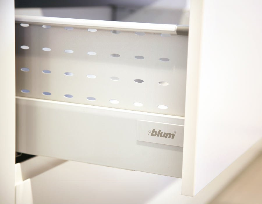 Wysuwana szuflada z metalowymi bokami, perforowana, z białym frontem i widocznym logo Blum.