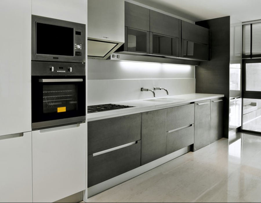 Nowoczesna kuchnia z białymi i grafitowymi szafkami, wbudowanym piekarnikiem i mikrofalówką oraz podświetleniem LED nad blatem.