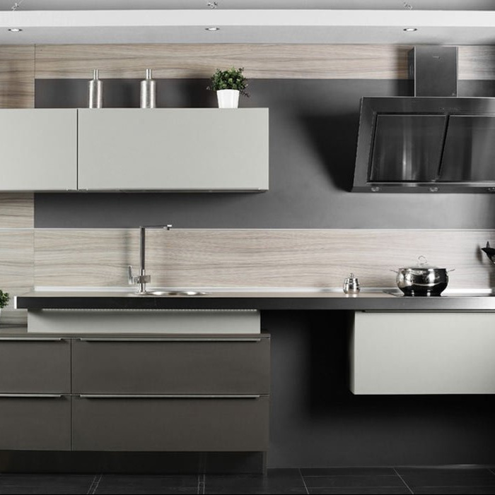 Nowoczesna kuchnia z szarymi i drewnopodobnymi frontami, minimalistyczna armatura i czarny okap, garnek na płycie, roślina doniczkowa na półce.