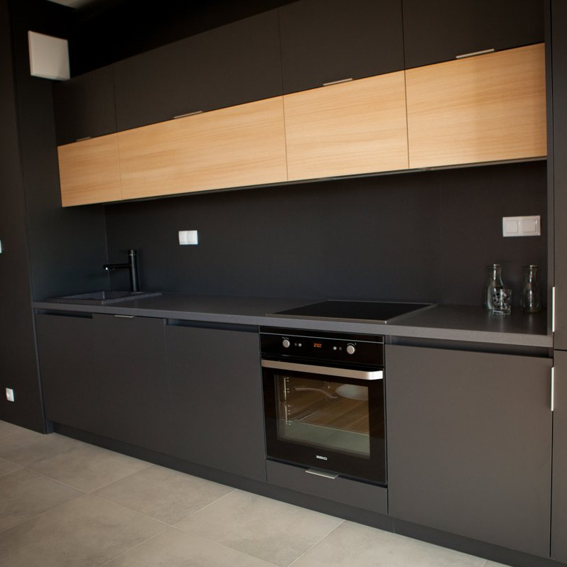 Nowoczesna kuchnia z ciemnoszarymi szafkami dolnymi i górnymi z drewnianymi frontami, minimalistyczny design, czarny blat, płyta indukcyjna i piekarnik Beko.