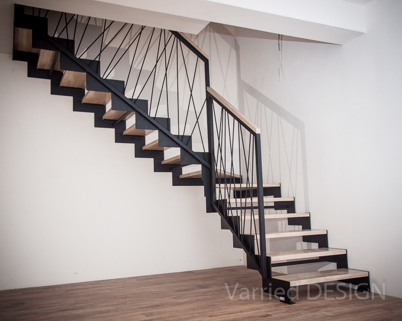 Nowoczesne schody metalowe z drewnianymi stopniami i minimalistyczną balustradą z cienkich prętów, oświetlone naturalnym światłem w jasnym wnętrzu.