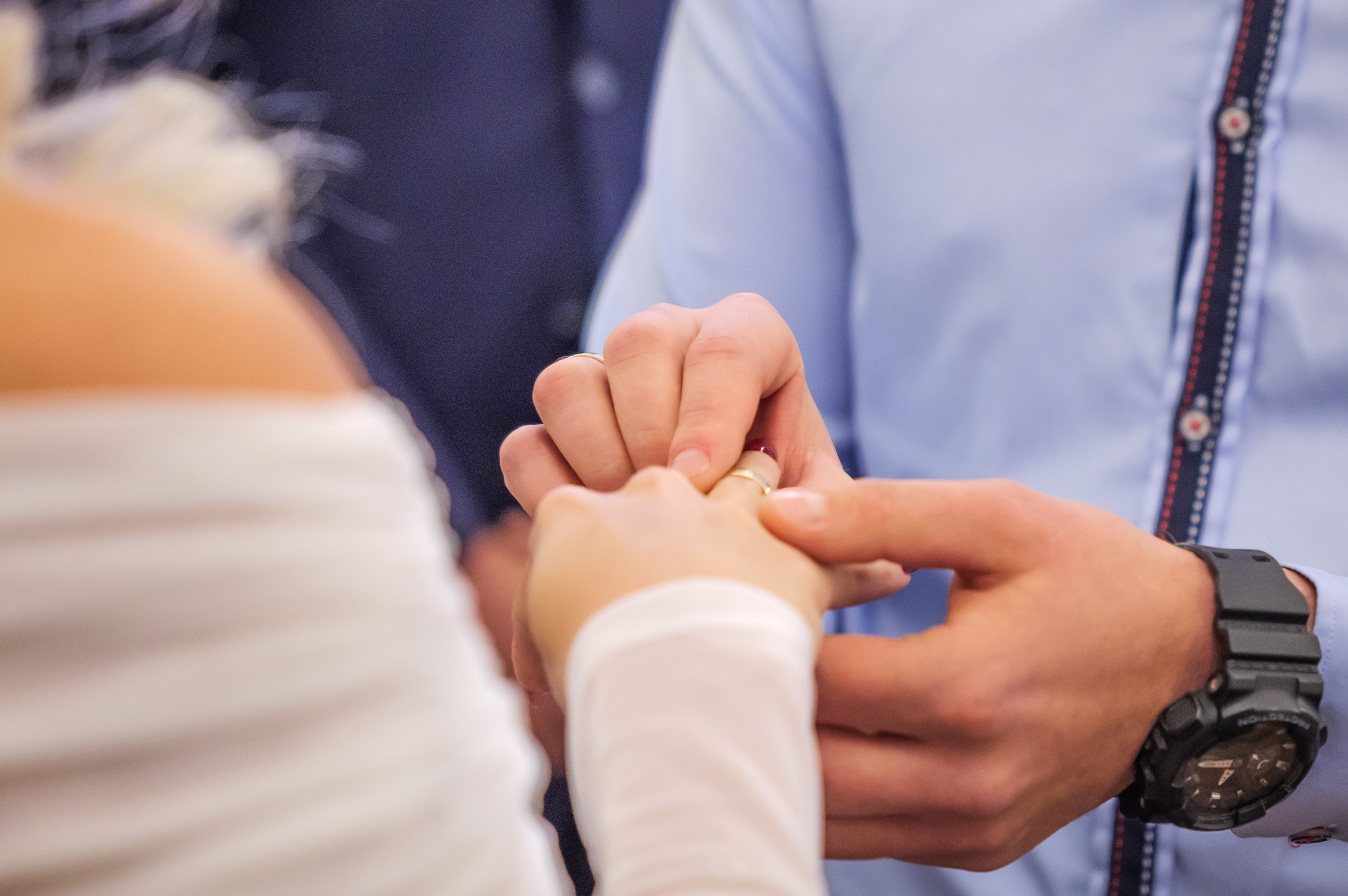 Moment zakładania obrączki podczas ceremonii ślubnej, widoczna dłoń panny młodej i pana młodego, zegarek na ręce pana młodego.