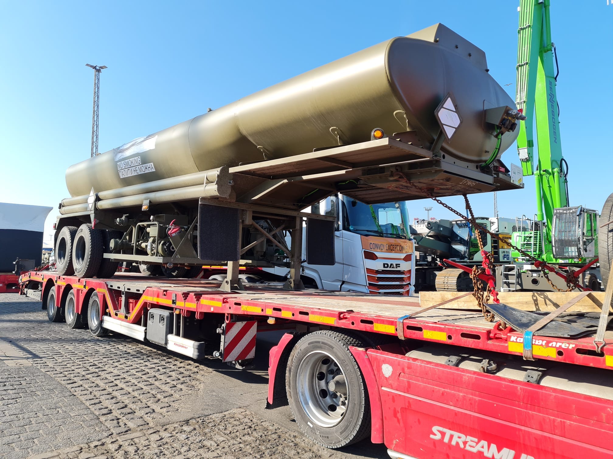 Ciężarówka z cysterną na naczepie niskopodwoziowej, transport specjalistyczny. Widoczny napis 'NO SMOKING' na cysternie i 'CONVOI EXCEPTIONNEL' na kabinie DAF.