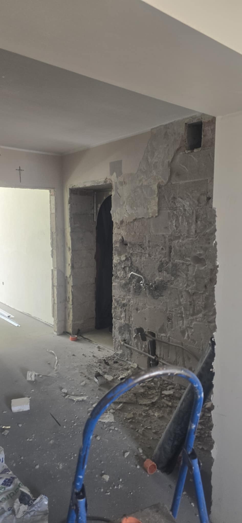 Wnętrze w trakcie remontu: odsłonięta cegła, instalacje, drabina malarska. Widoczne ślady prac demontażowych i przygotowawczych do dalszych etapów wykończenia.