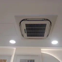 Kasetonowa klimatyzacja sufitowa wkomponowana w eleganckie wnętrze, widok z dołu, z dwoma punktowymi lampami LED w pobliżu.