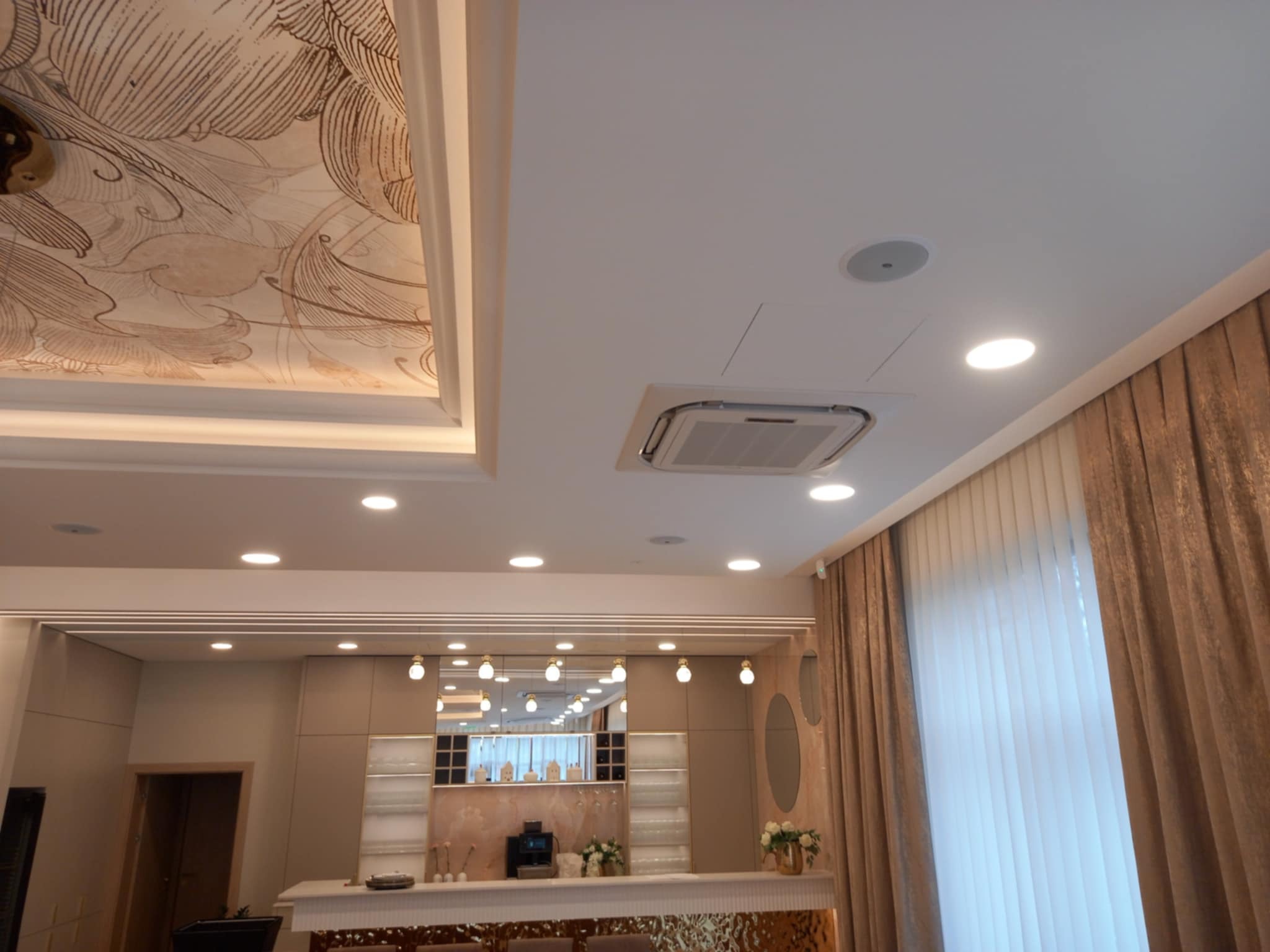 Kaseton klimatyzacji sufitowej w eleganckim wnętrzu w Gdyni. Widoczne oświetlenie punktowe i dekoracyjny sufit. Klimatyzacja do domu.