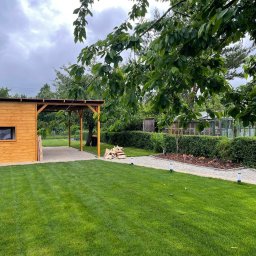 KONSTANTYN PYSHNIAK - Zadbany ogród z równo przystrzyżonym trawnikiem, drewnianą altaną z kostką brukową i ścieżką z oświetleniem, prowadzącą w głąb działki.