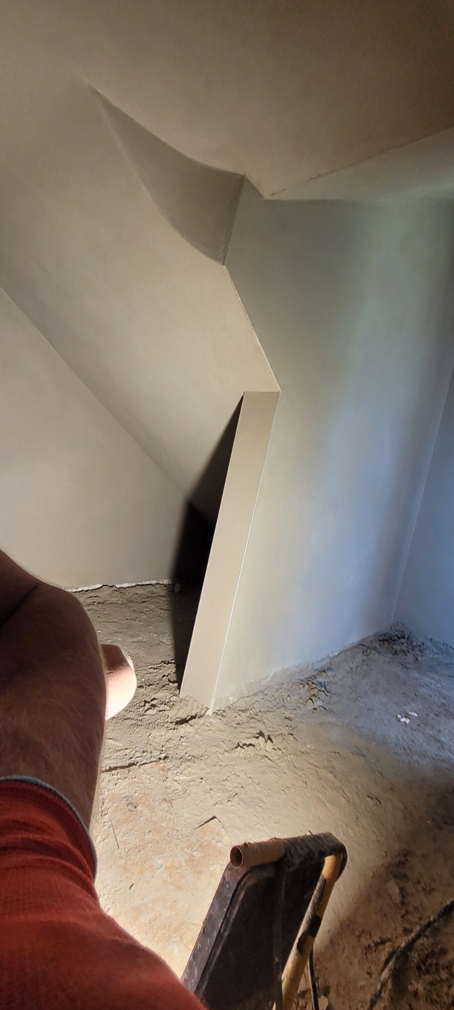 Wygładzone ściany poddasza po tynkowaniu w Żywcu. Widoczny fragment wózka i niedoskonałości podłoża przed dalszymi pracami wykończeniowymi.