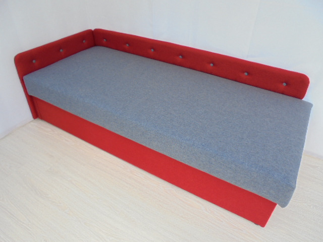 Tapczan w czerwonej tapicerce z szarym siedziskiem, widoczne guziki na oparciu, minimalistyczny design.