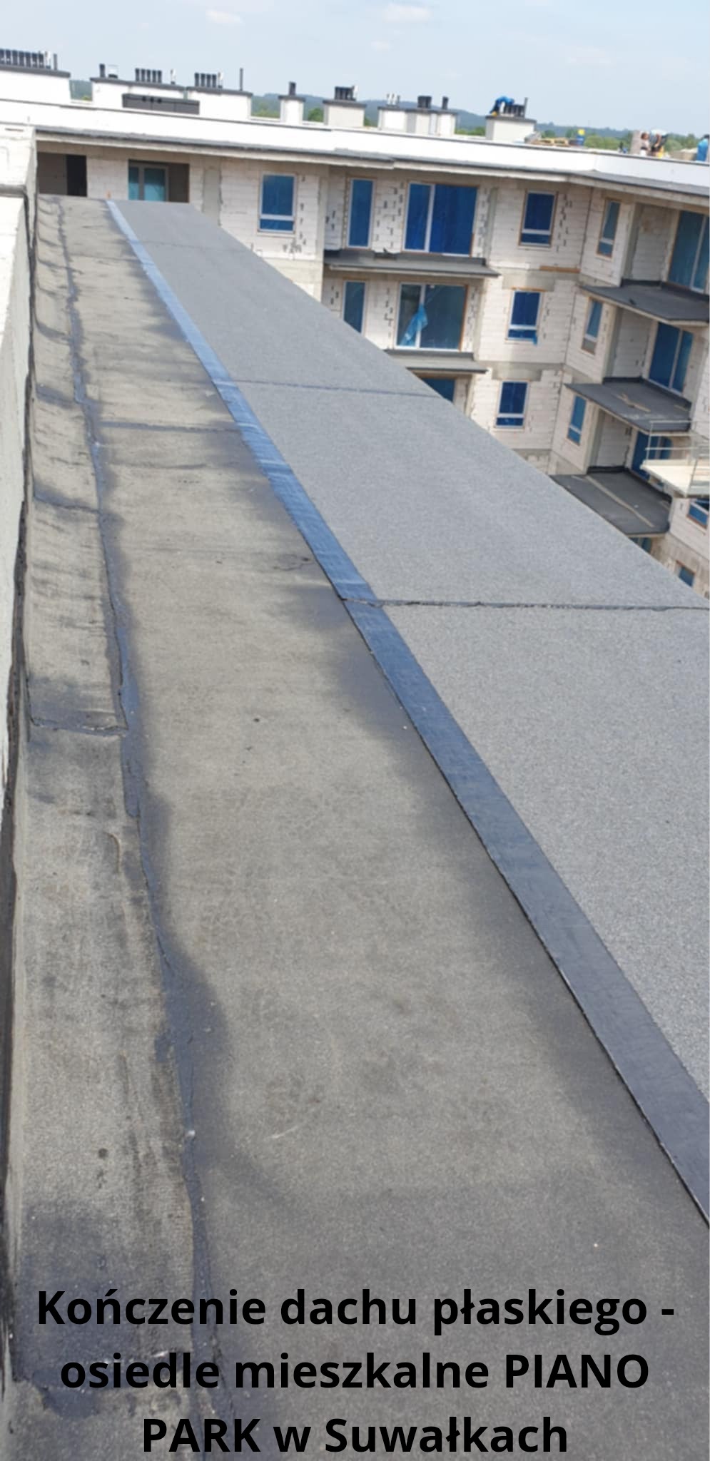 Wykończony fragment płaskiego dachu z papy termozgrzewalnej na tle budynku mieszkalnego w jasnej kolorystyce. Widoczne łączenia papy.