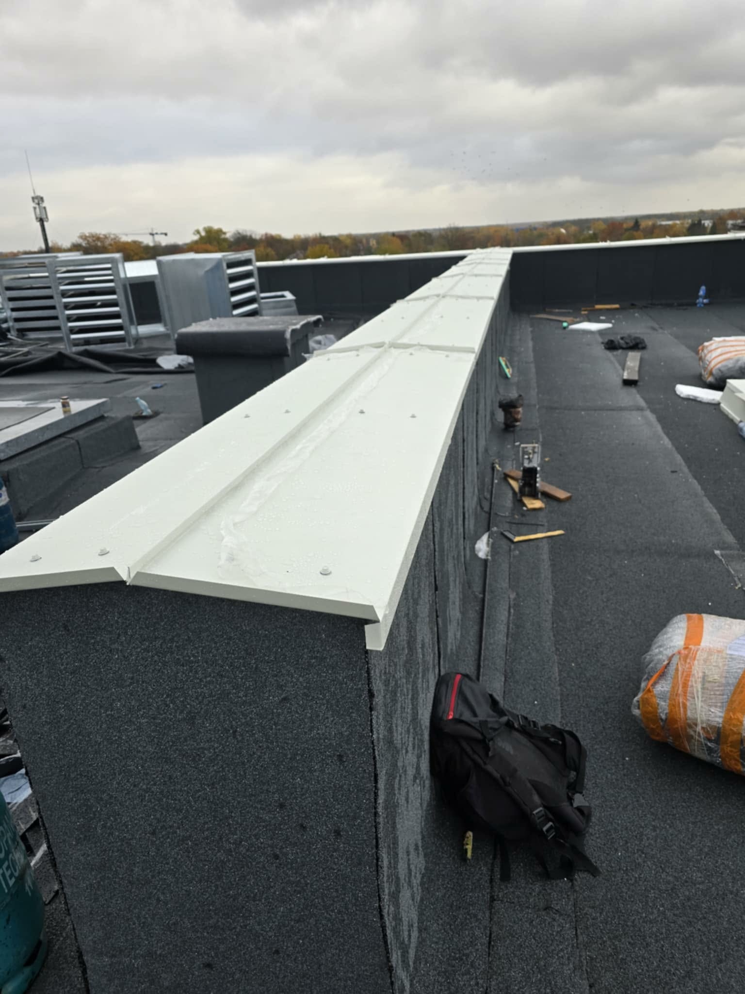 Wykończona attyka dachu płaskiego z blachy w Suwałkach. Widoczne narzędzia i materiały dekarskie. Praca wykonana z dbałością o detale.