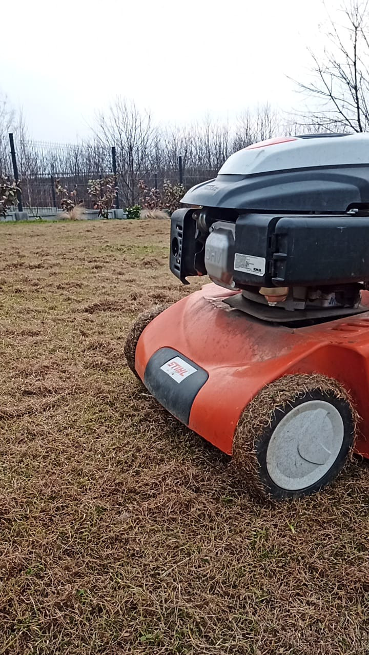 Pomarańczowa kosiarka spalinowa Stihl na trawniku z uschniętą trawą, widoczne ślady koszenia.