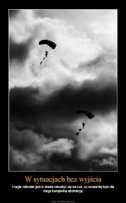 Dwa czarne spadochrony na tle dramatycznych, ciemnych chmur burzowych. Spadochroniarze lecą w dół, a pod nimi widoczne są fragmenty linek. U dołu kadru umieszczony jest tekst w języku polskim.
