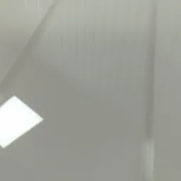 Błyszcząca, biała płyta z widocznymi pionowymi liniami odbicia światła, sugerująca powierzchnię blatu lub panelu.