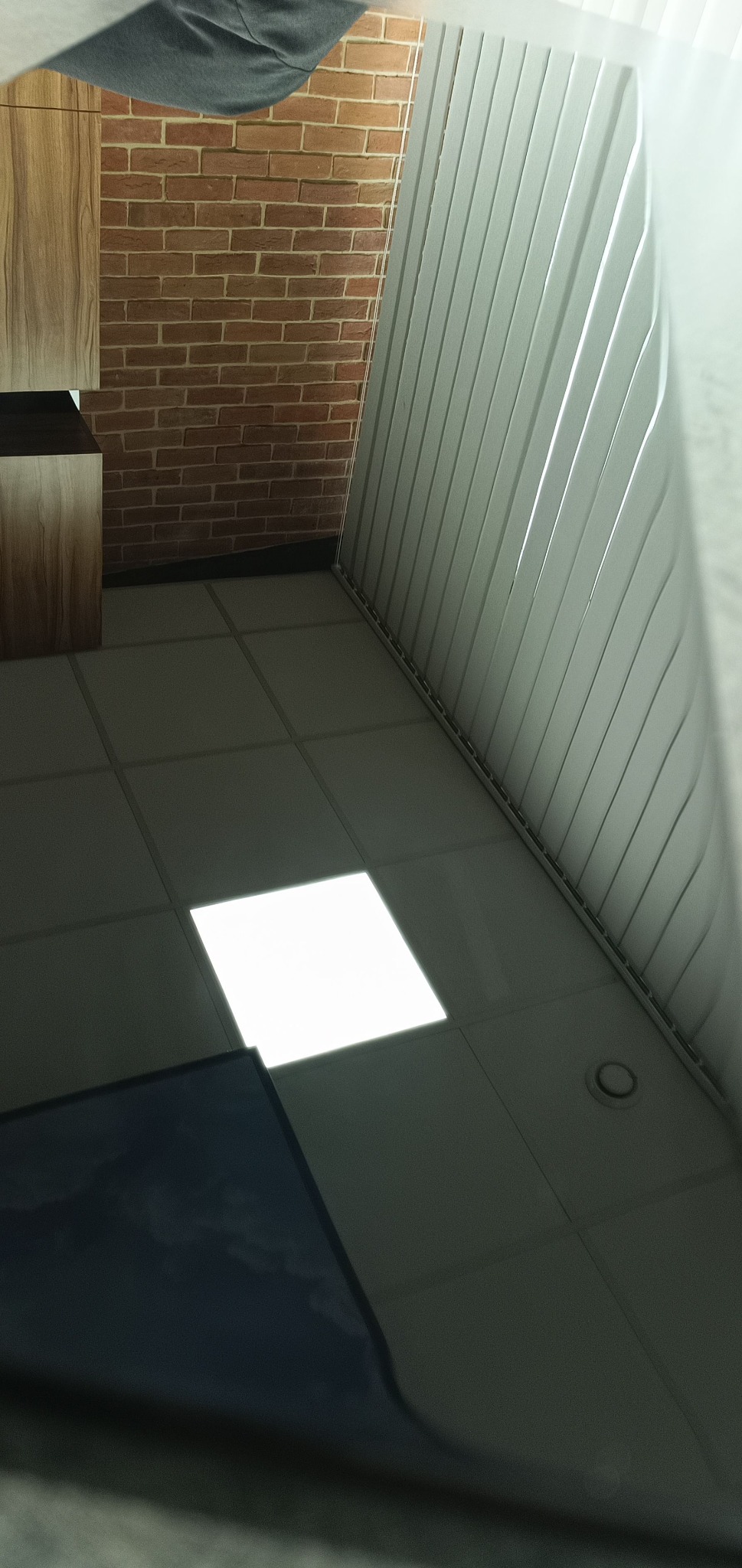 Fragment wnętrza z bliska: zabudowa meblowa z drewnianymi frontami, ceglana ściana, białe żaluzje i podłoga z jasnych płytek.