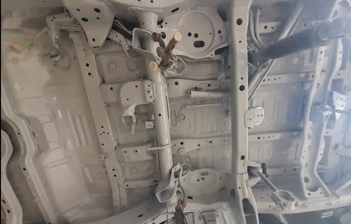 Podwozie samochodu po piaskowaniu i zabezpieczeniu antykorozyjnym, pomalowane na jasnoszary kolor, widoczne elementy zawieszenia i konstrukcji nośnej.