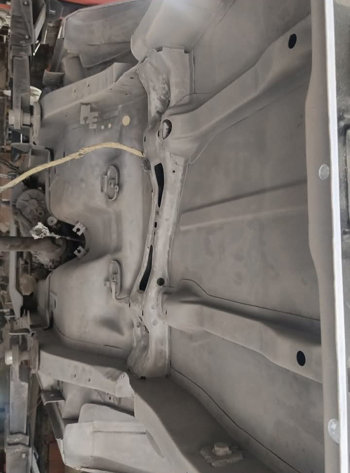 Podwozie samochodu po piaskowaniu i zabezpieczeniu antykorozyjnym, widoczne elementy konstrukcyjne w szarym podkładzie, przygotowane do dalszych prac.