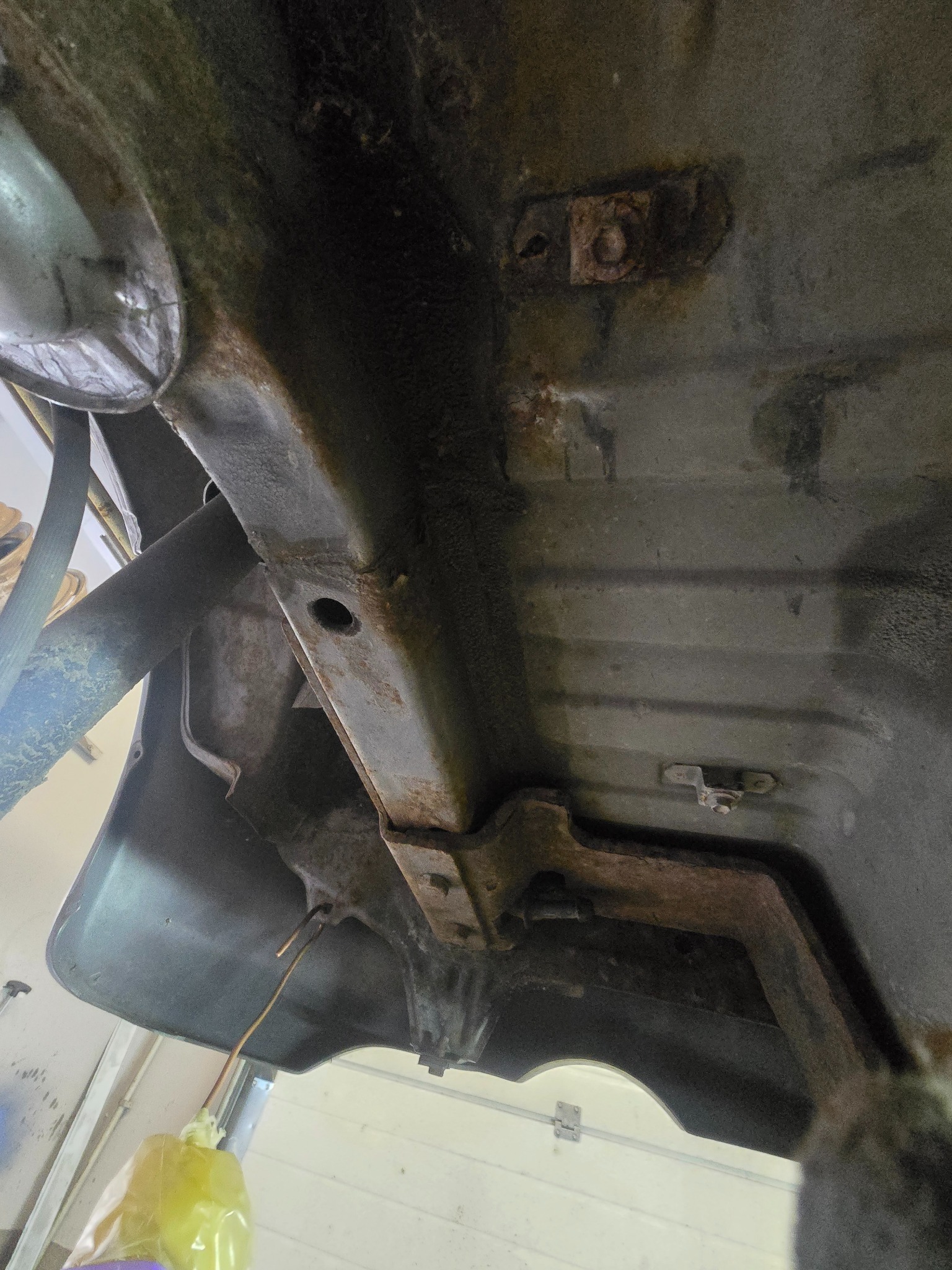 Podwozie samochodu z widoczną rdzą na metalowych elementach. Widoczne ślady korozji, metalowe profile i elementy mocujące. Perspektywa od dołu.