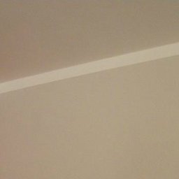 Damian Wyrzykowski - Pomieszczenie po malowaniu: czerwona ściana kontrastuje z beżową, oddzielone białym, dekoracyjnym pasem pod sufitem. Widoczny róg pokoju i fragment sufitu.