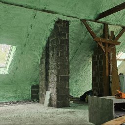 Łukasz Morawiec - Poddasze po ociepleniu pianką PUR, widoczne drewniane elementy konstrukcyjne, okno dachowe i komin z cegły. Ściany i sufit pokryte jednolitą warstwą izolacji.