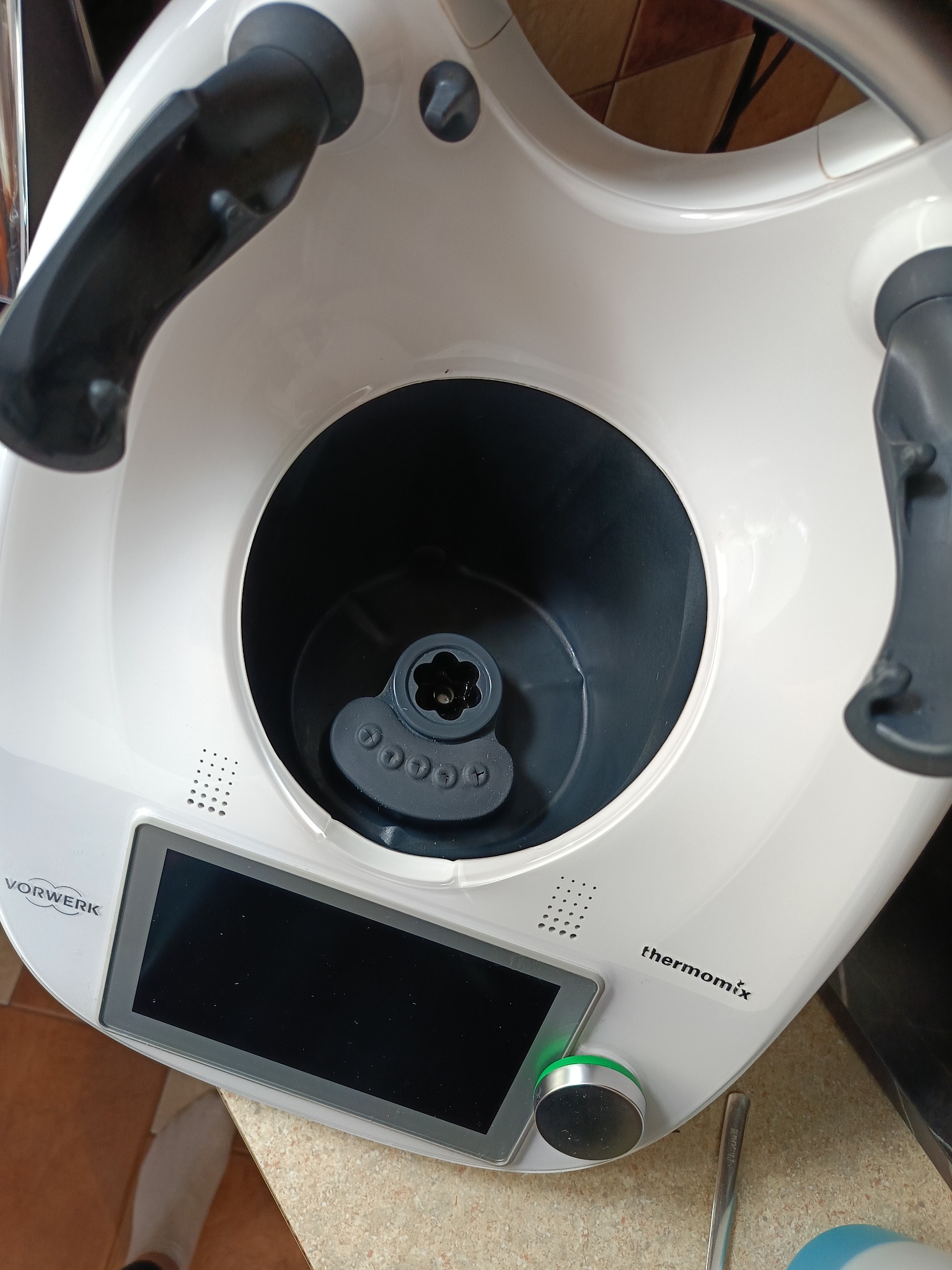 Biały Thermomix Vorwerk z pustym naczyniem miksującym, widok z góry na blat kuchenny. Widoczny panel dotykowy i pokrętło sterowania.