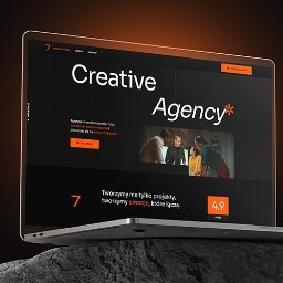 JAID - Laptop prezentuje stronę internetową agencji kreatywnej z ciemnym motywem, pomarańczowym akcentem i zdjęciem zespołu. Widoczny fragment skały w tle dodaje unikalności.