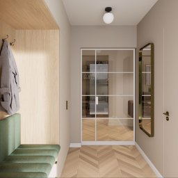 The Plan sp. z o.o. - Wnętrze przedpokoju z siedziskiem, wieszakami na ubrania i lustrem. Podłoga wyłożona parkietem w jodełkę. Widoczne drzwi z przeszkleniami i oświetlenie sufitowe.
