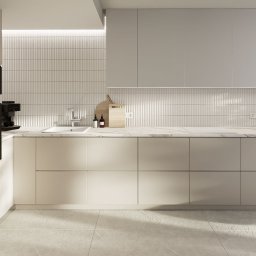 The Plan sp. z o.o. - Jasna kuchnia z beżowymi frontami szafek, marmurowym blatem i podłużnymi płytkami na ścianie. Minimalistyczny design z drewnianymi deskami i dozownikami na blacie.