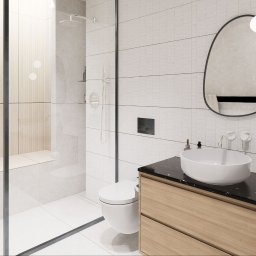 The Plan sp. z o.o. - Nowoczesna łazienka z kabiną prysznicową typu walk-in, umywalką na blacie z czarnego marmuru i lustrem o nieregularnym kształcie. Jasna kolorystyka i minimalistyczny design.