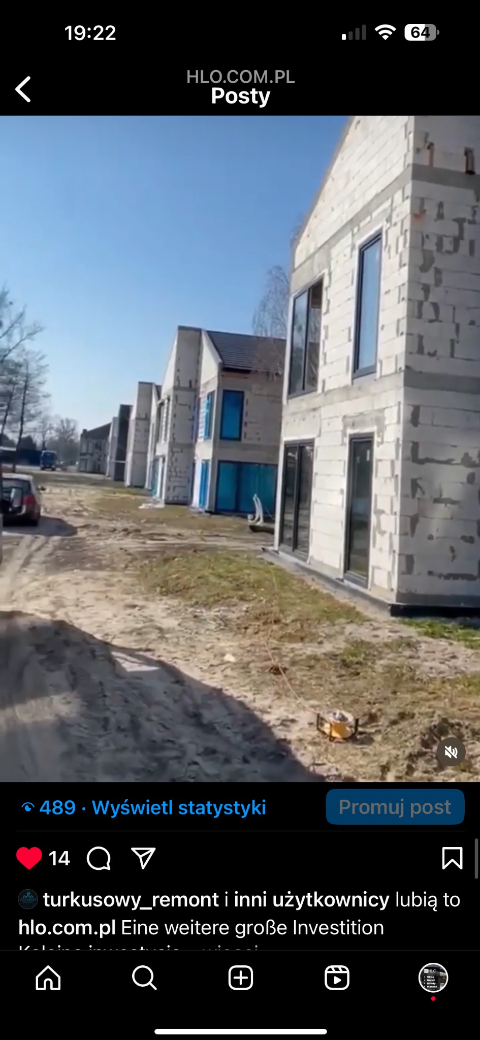 Rząd surowych domów w stanie deweloperskim z zamontowanymi oknami i drzwiami, widok z zewnątrz, na pierwszym planie ziemia i narzędzie budowlane.