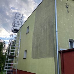 Jarek Wachowiak - Fragment elewacji budynku z widocznym efektem mycia pod ciśnieniem, kontrast między umytą a brudną powierzchnią, aluminiowa drabina przystawiona do ściany, rynna pionowa.